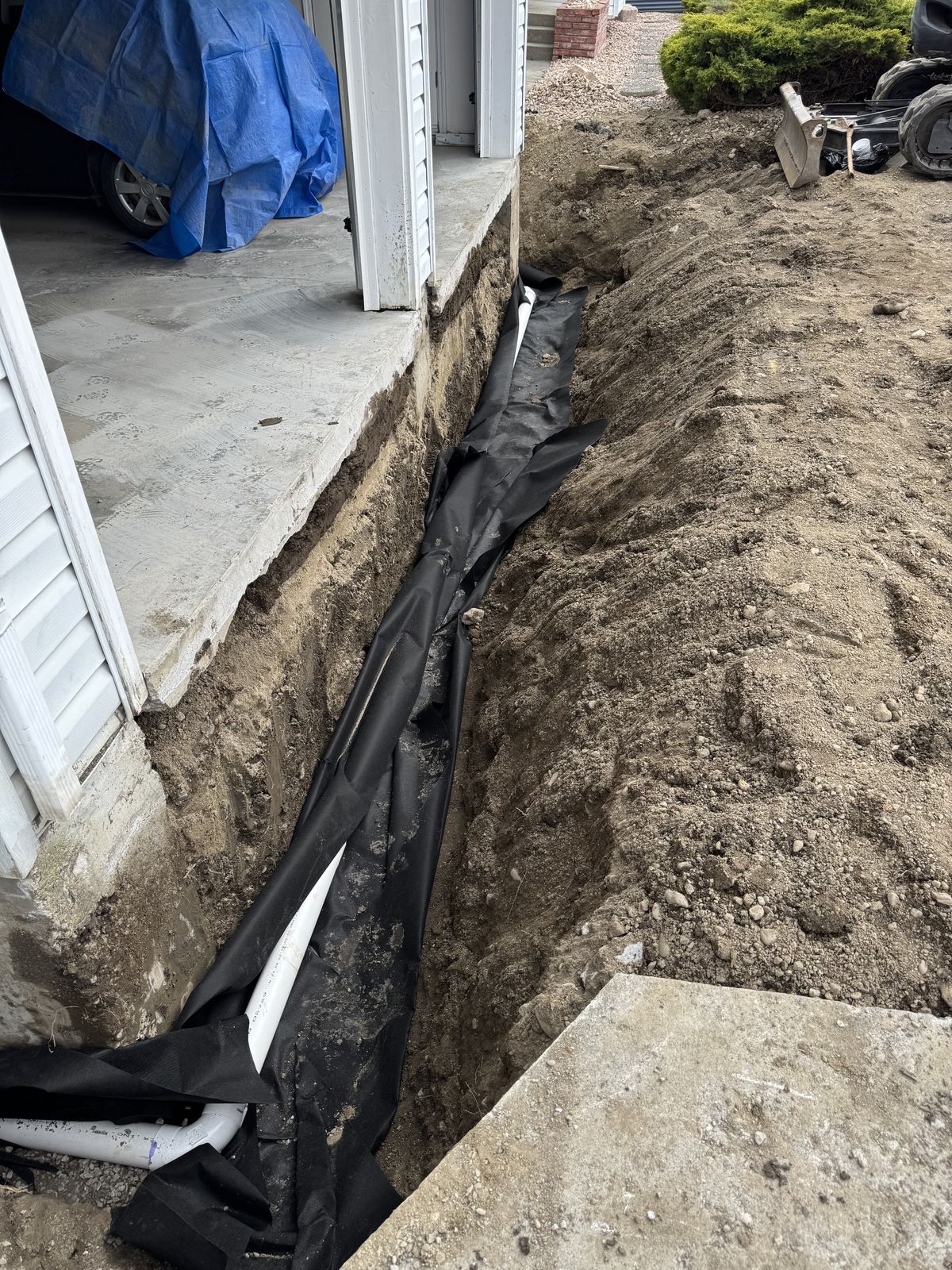 Foundation drain pipe and filter fabric in a narrow side-yard trench