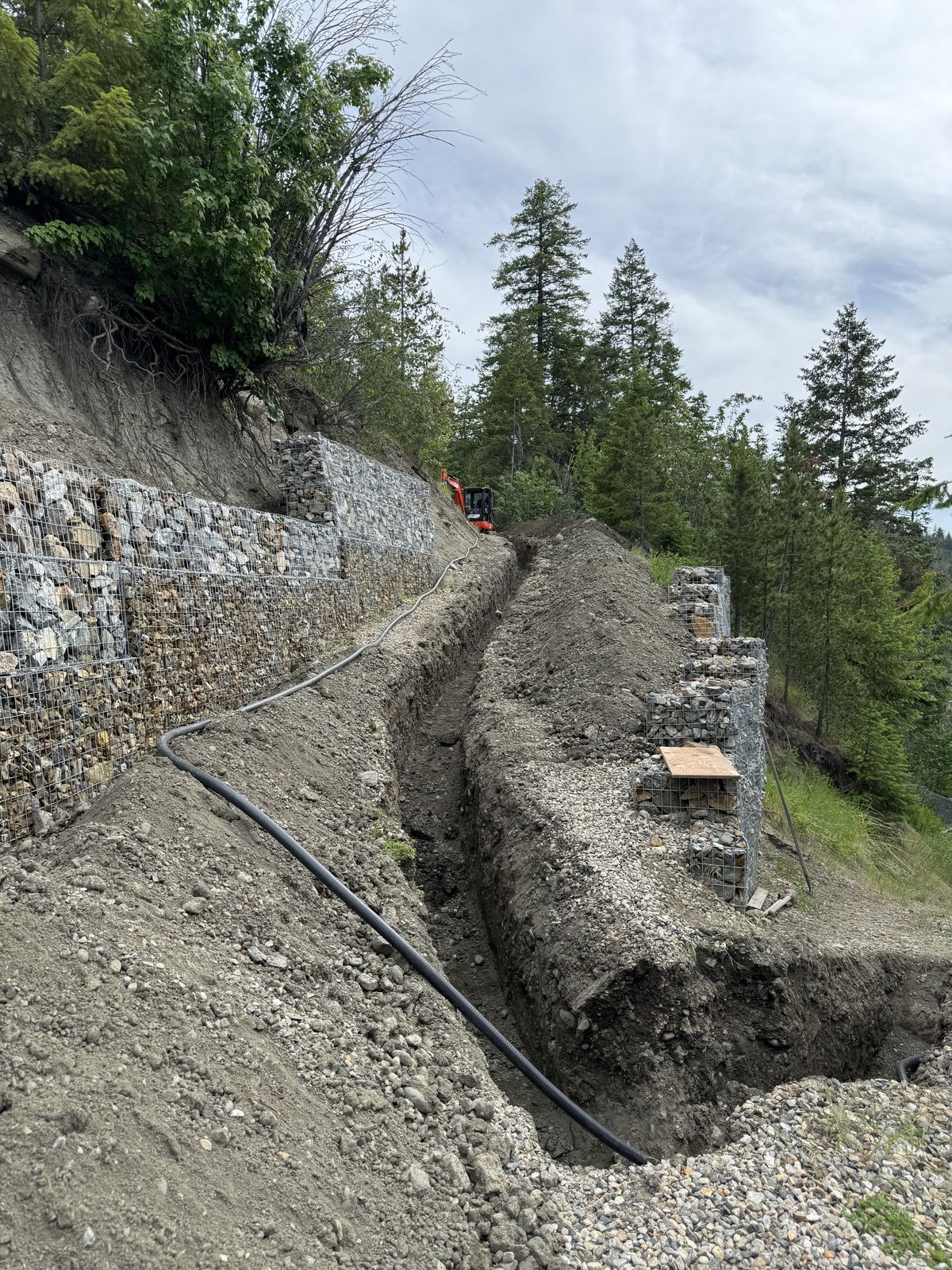 Gabion rock wall and drainage trench on a lakeside slope above Okanagan Lake