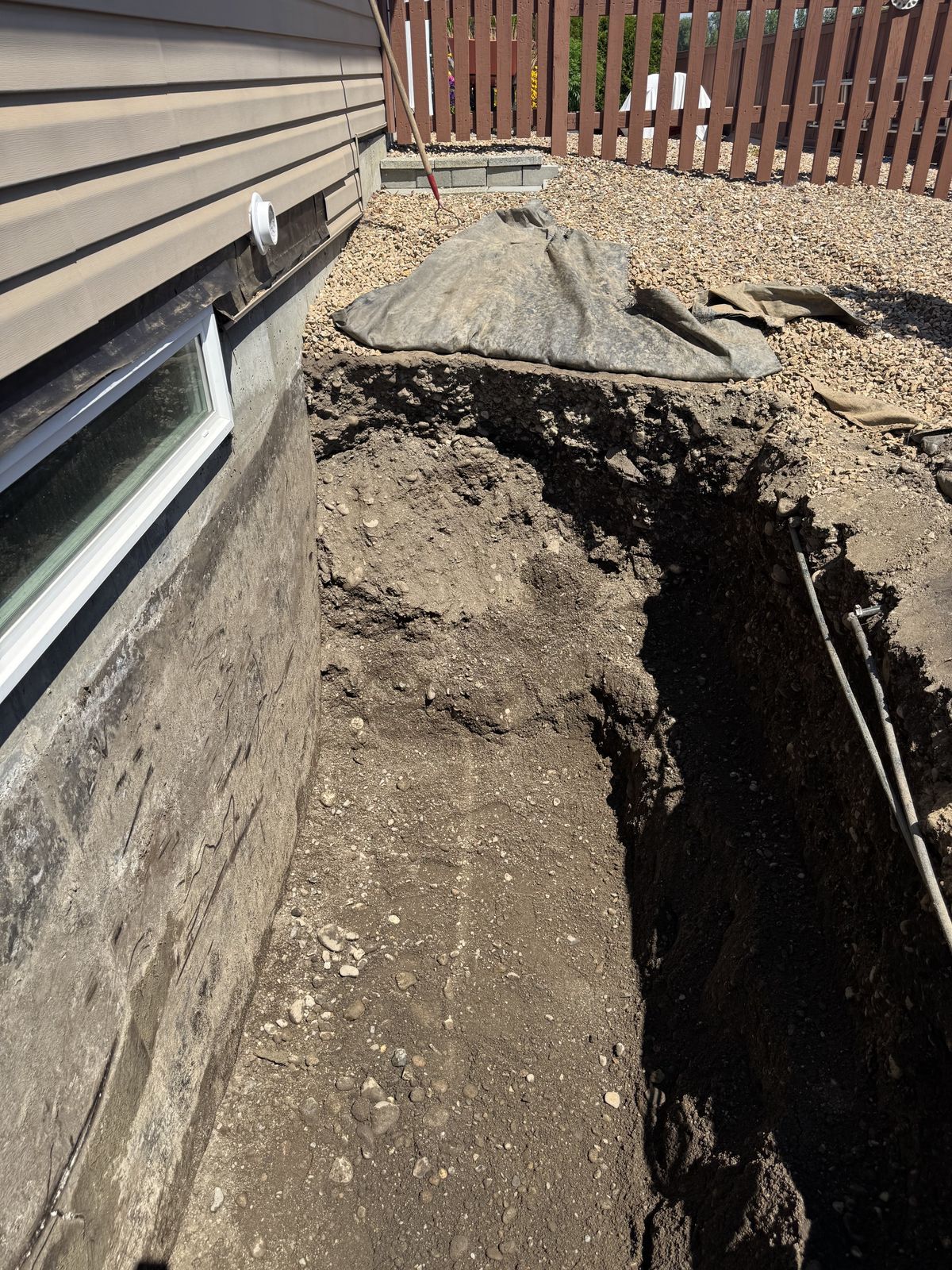 Deep drainage trench along a house foundation